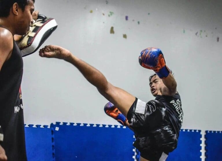 Athlete delivering a powerful roundhouse kick during an advanced kickboxing training session.