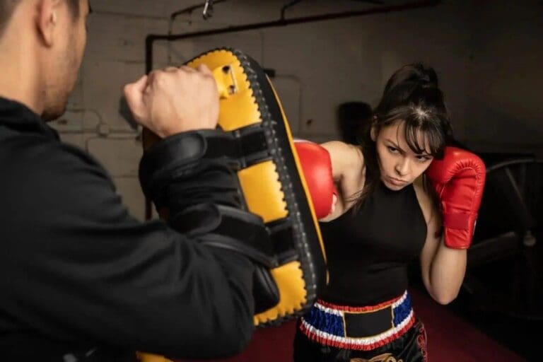 Woman practicing punch combinations with a trainer during a kickboxing class in Victoria.