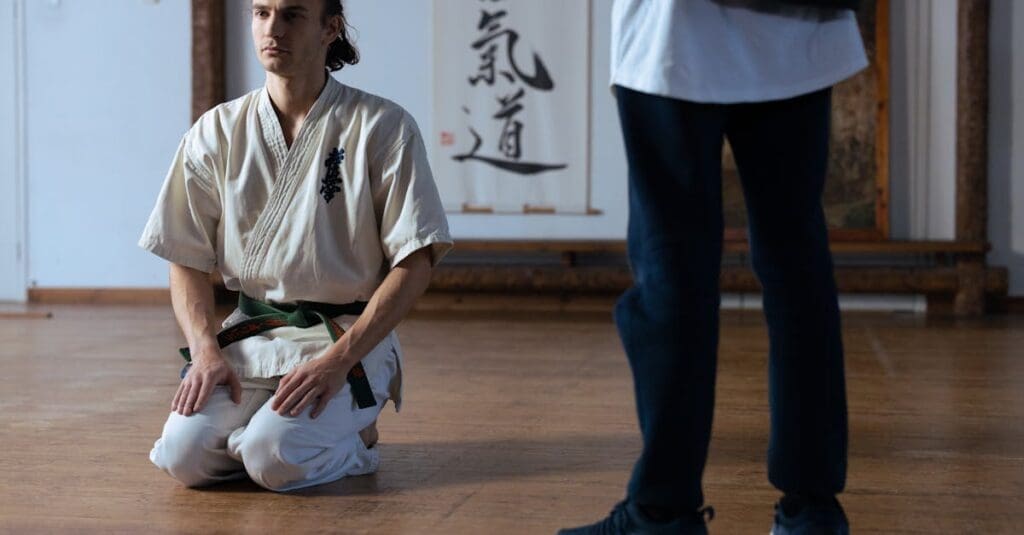 Beginner student observing class etiquette before instruction during martial arts training for beginners