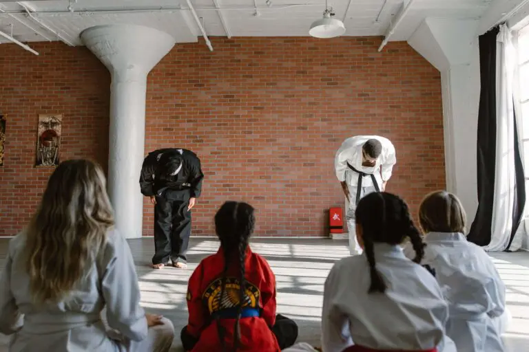 Martial arts instructors bowing to seated students at the beginning of class in a traditional dojo setting, first martial arts class experience.